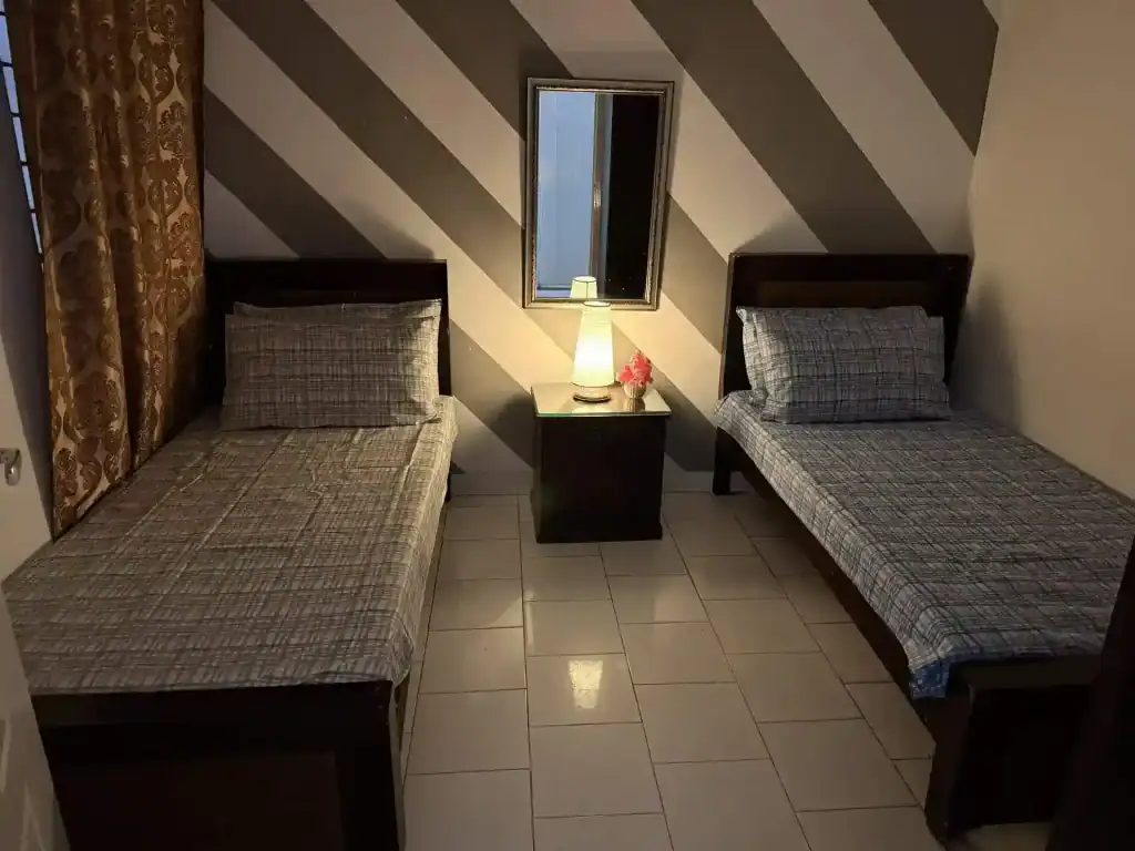 Cozy hostel room with two single beds in Lahore Girls Hostel.