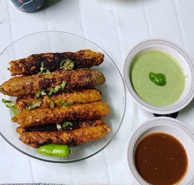 Traditional Pakistani food with grilled kebabs and green and brown chutneys at Lahore Girls Hostel.